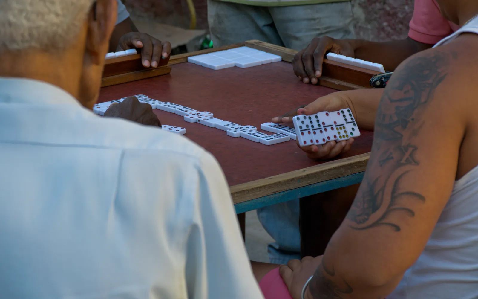 People playing dominoes at an outdoor table in Cuba